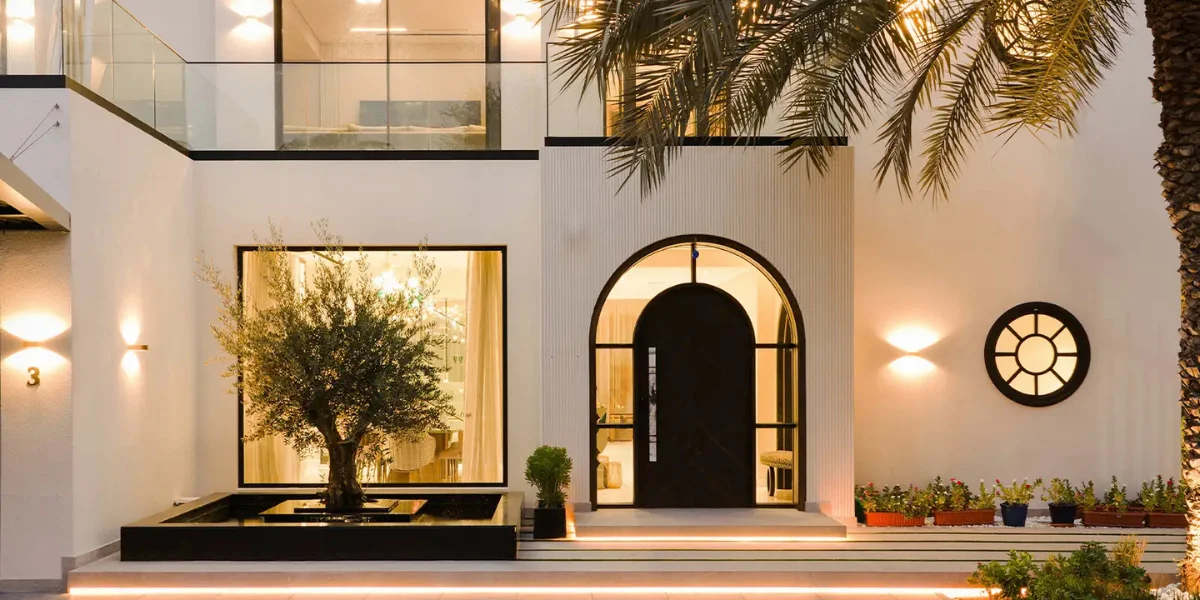 Contemporary villa entrance designed by Sumessh Menon Associates with a black arched doorway, reflecting pool, and minimalist architectural lighting.