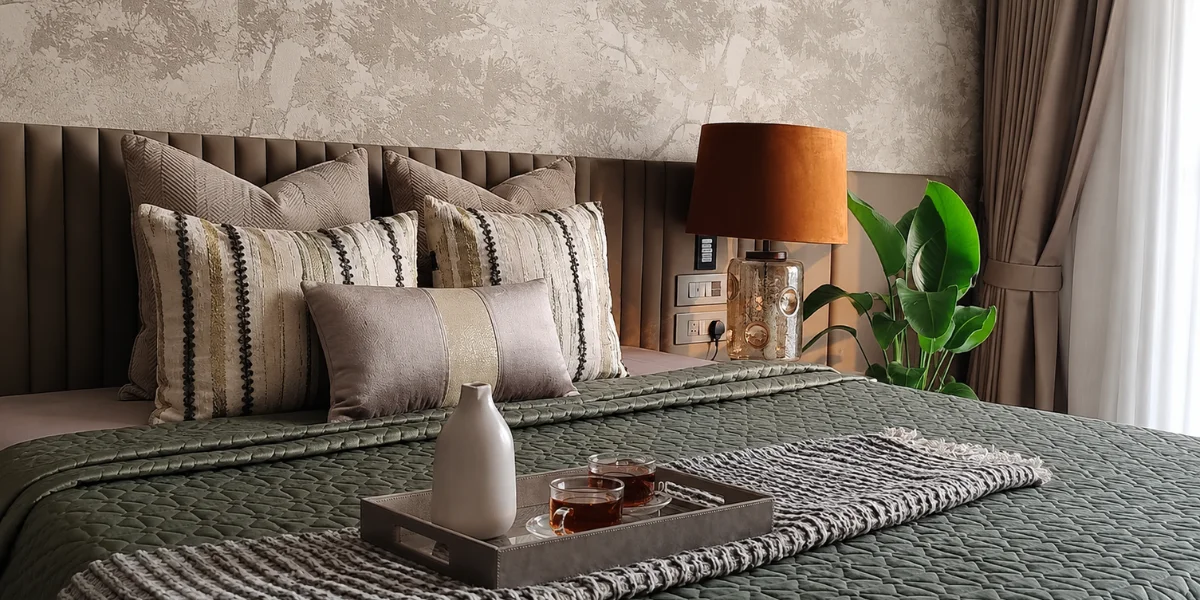 Elegant master bedroom interior by Sumessh Menon Associates with a sage green quilted bedspread and a custom channel-tufted leather headboard.