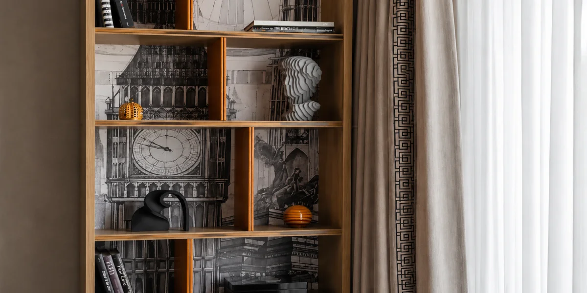 Bespoke wooden bookshelf with architectural wallpaper backing and curated decor, a design concept by Sumessh Menon Associates.